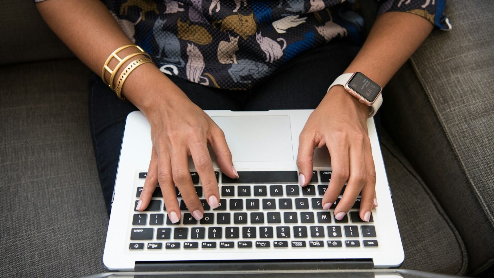 A top-down view of hands typing on a laptop keyboard.
