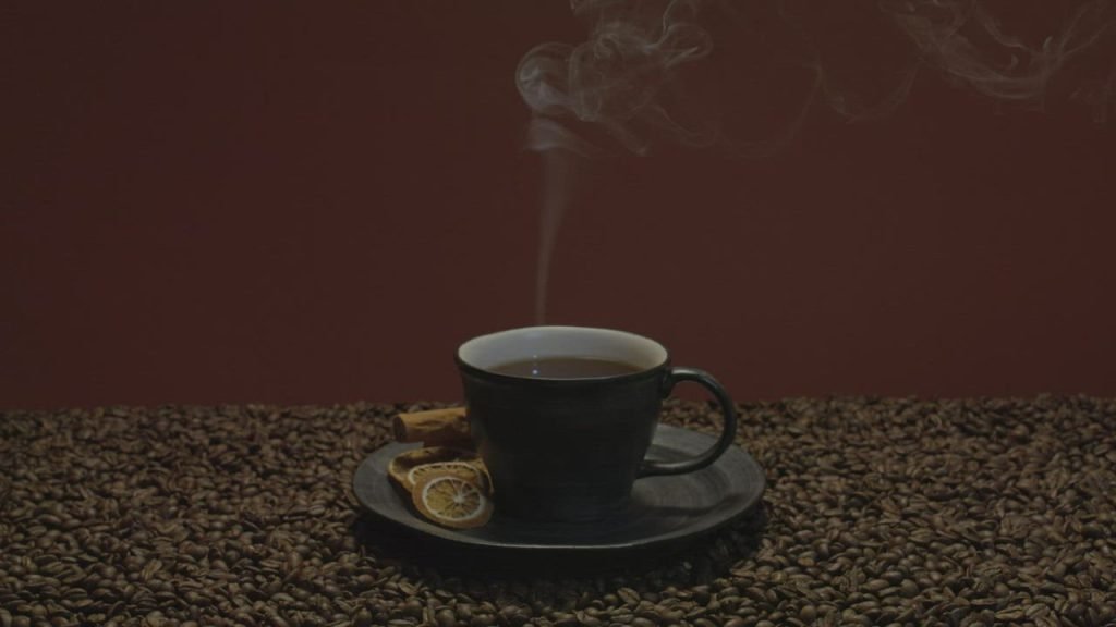 A steaming cup of coffee on a bed of roasted coffee beans