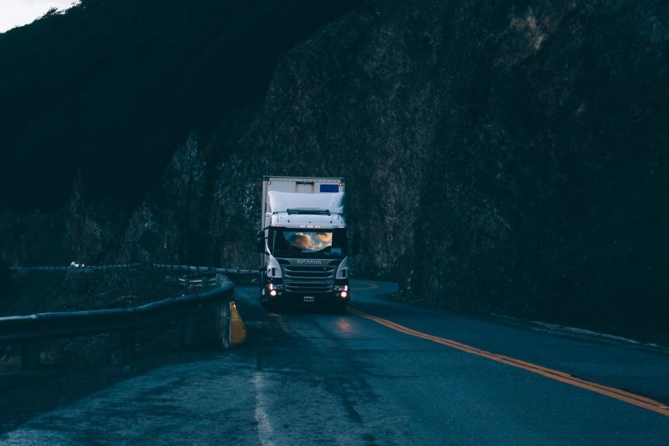 A delivery truck driving along a mountain road at dusk