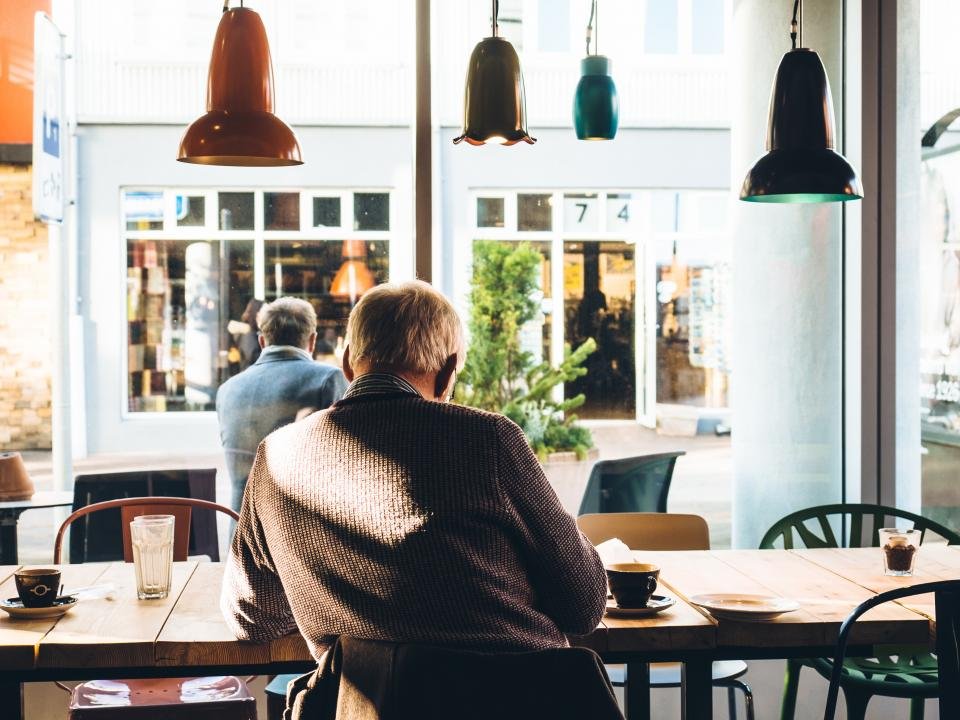 A customer at a table in a bright cafe with pendant lamps