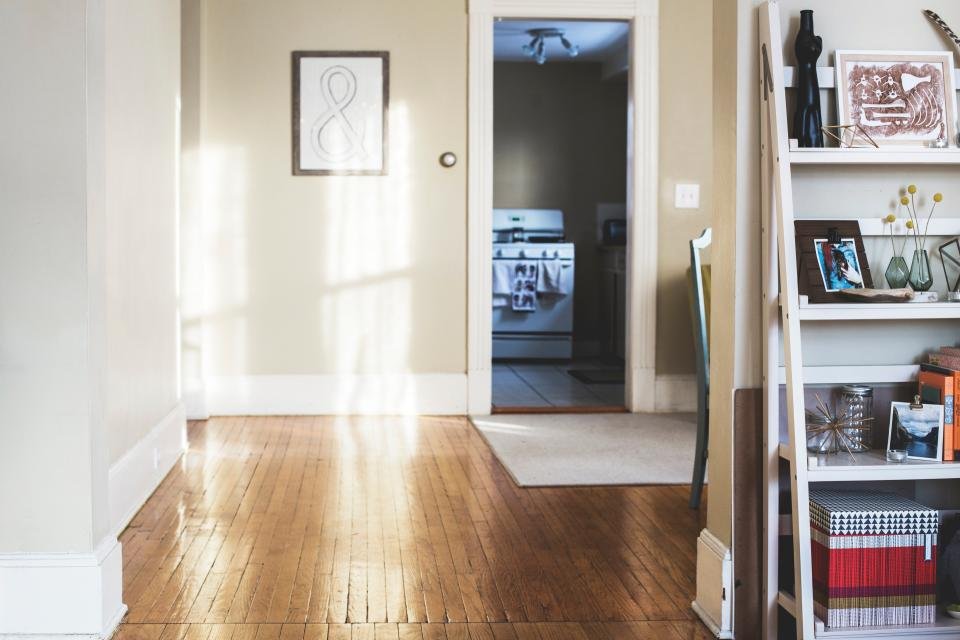 A bright hallway with a wooden floor and a shelf of decor
